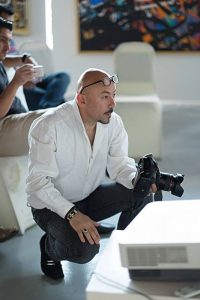 Portrait of Hoss  of Hoss Photography crouching holding his camera